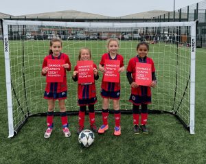 North Cardiff Cosmos Under 8 Girls team holding red cards to support the Show Racism the Red Card campaign.